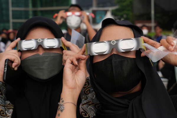 Женщины в&nbsp;защитных очках наблюдают за&nbsp;солнечным затмением в&nbsp;Джакарте, Индонезия, 20&nbsp;апреля 2023&nbsp;года.