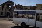 Местные жители в автобусе на фоне разрушенных зданий в результате боевых действий в Константиновке, Украина, 10 апреля 2024 года