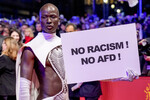 Гость Берлинского кинофестиваля держит табличку «Нет расизму и АдГ (ультраправая партия в Германии)», 15 февраля 2024 года