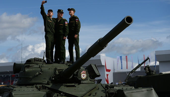 Военнослужащие фотографируются на фоне образцов военной техники в открытой экспозиции на...