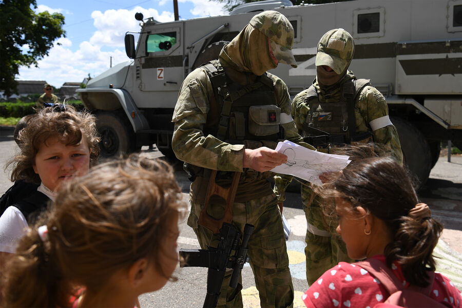 Военнослужащие РФ рассматривают рисунок от учеников школы в одном из населенных пунктов в Запорожской области, июль 2022 года