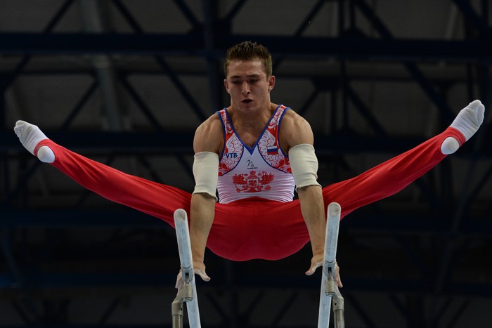 Российский гимнаст Давид Белявский выполняет упражнение на брусьях