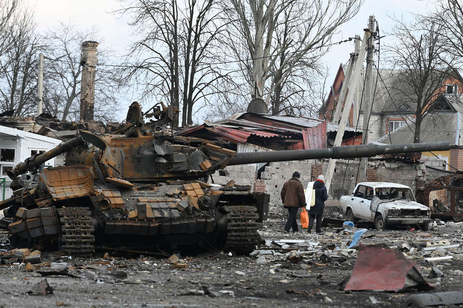 Жители Волновахи идут домой мимо разбитого танка Вооруженных сил Украины
