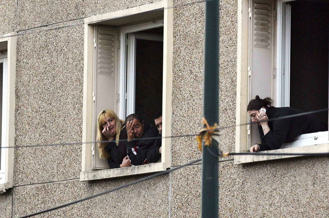 Жители соседних домов наблюдают за действиями полиции, осаждающей квартиру предполагаемого убийцы