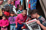 Албанские беженцы в лагере читают статью о бомбардировках Югославии в местной газете, 25 марта 1999 года
