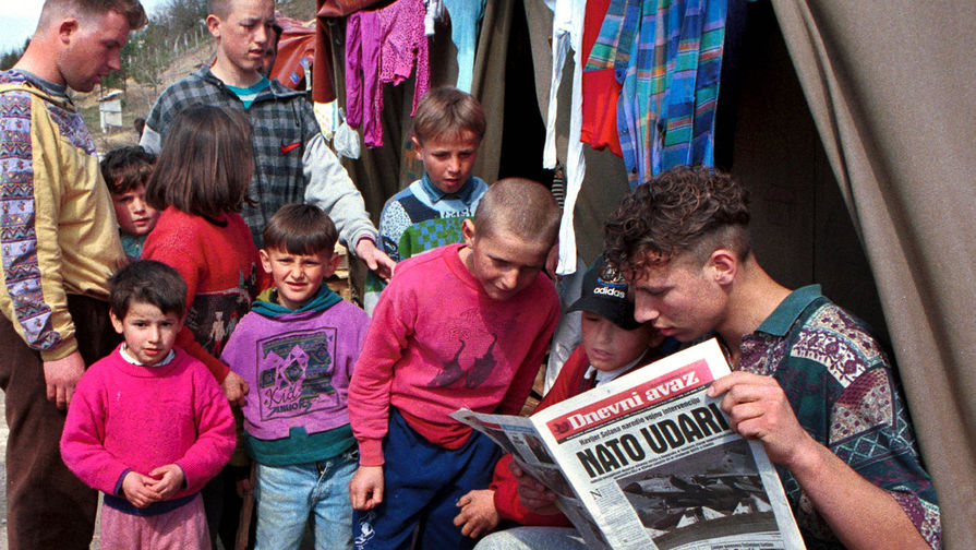 Албанские беженцы в лагере читают статью о бомбардировках Югославии в местной газете, 25 марта 1999 года