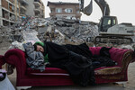 Мужчина спит на диване возле обрушившегося здания в результате мощных землетрясений в Хатае, Турция, 13 февраля 2023 года