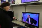 Жительница города смотрит трансляцию большой пресс-конференции президента РФ Владимира Путина в магазине «М.Видео» в Москве