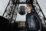 Американский уличный художник Шепард Фейри позирует на фоне своей инсталляции «Кризис Земли» между первым и вторым этажом Эйфелевой башни в Париже
