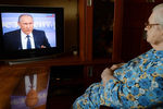 Жительница Москвы смотрит телетрансляцию одиннадцатой большой ежегодной пресс-конференции президента России Владимира Путина