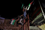 Ливанские протестующие размахивают палестинскими флагами, взбираясь на забор посольства США в Бейруте, 17 октября 2023 года 