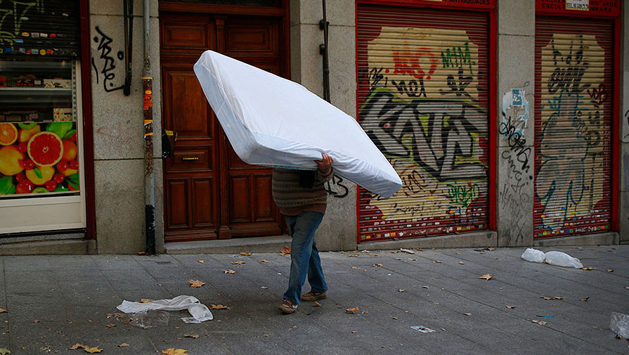 Мужчина несет матрас по улице Мадрида во время забастовки профсоюзов уборщиков, ноябрь 2013 года
