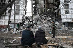 Боец Народной милиции ДНР и местные жители во дворе разрушенного дома в Мариуполе, апрель 2022 года
