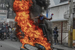 Протестующий перепрыгивает через горящие шины во время акции протеста против премьер-министра Гаити Ариэля Генри в Порт-о-Пренсе, Гаити, 5 февраля 2024 года.