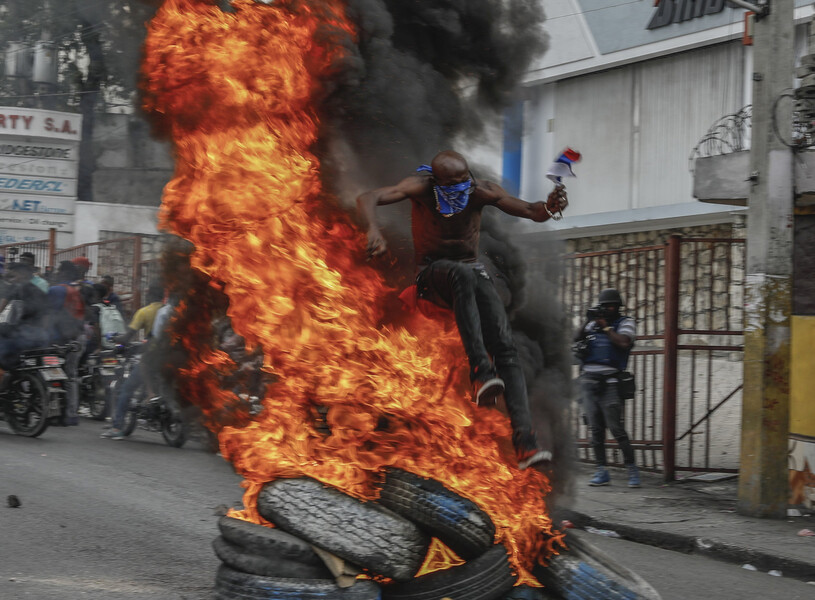Протестующий перепрыгивает через&nbsp;горящие шины во время акции протеста против премьер-министра Гаити Ариэля Генри в&nbsp;Порт-о-Пренсе, Гаити, 5&nbsp;февраля 2024&nbsp;года.