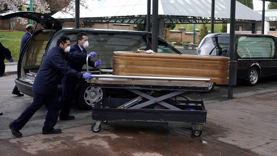 Работники морга с гробом с телом жертвы коронавируса COVID-19 около крематория в Мадриде, 23 марта 2020 года