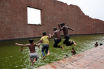 Дети прыгают в воду мемориала замученных интеллектуалов в Райербазаре, Дакка, Бангладеш, 23 апреля 2024 года