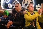 Пассажиры в новогоднем поезде московского метро, украшенном гирляндами и еловыми ветками
