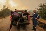 Мигранты прыгают в пожарную машину во время лесного пожара в национальном парке Дадия в регионе Эврос, Греция, 1 сентября 2023 года