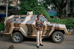 Сотрудник спецподразделения полиции Индии около бронированного автомобиля