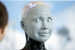 Человекоподобный робот «Амека» взаимодействует с участником саммита ООН, посвященного вопросам развития и применения искусственного интеллекта, в Женеве, 6 июля 2023 года