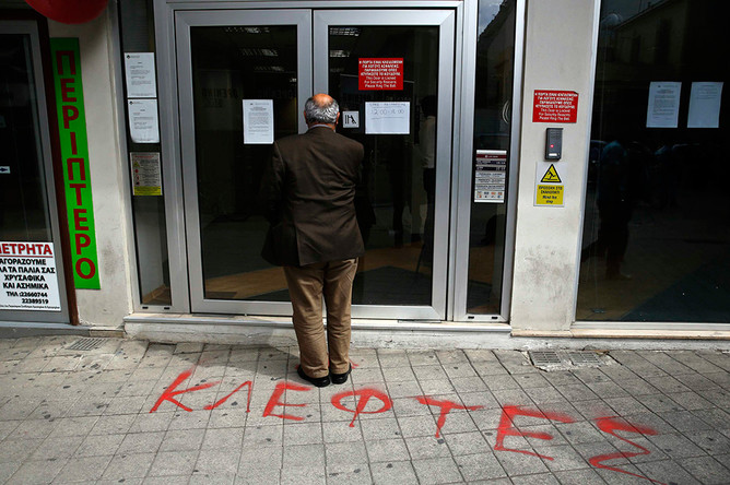 Вкладчик у дверей кипрского банка. Надпись на тротуаре: «Воры»