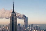 Башни-близнецы Всемирного торгового центра горят за зданием Эмпайр-стейт-билдинг после теракта 11 сентября 2001 года
