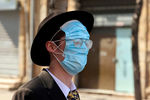 Мужчина с тремя защитными масками на лице во время празднования Пурима, Иерусалим, февраль 2021 года