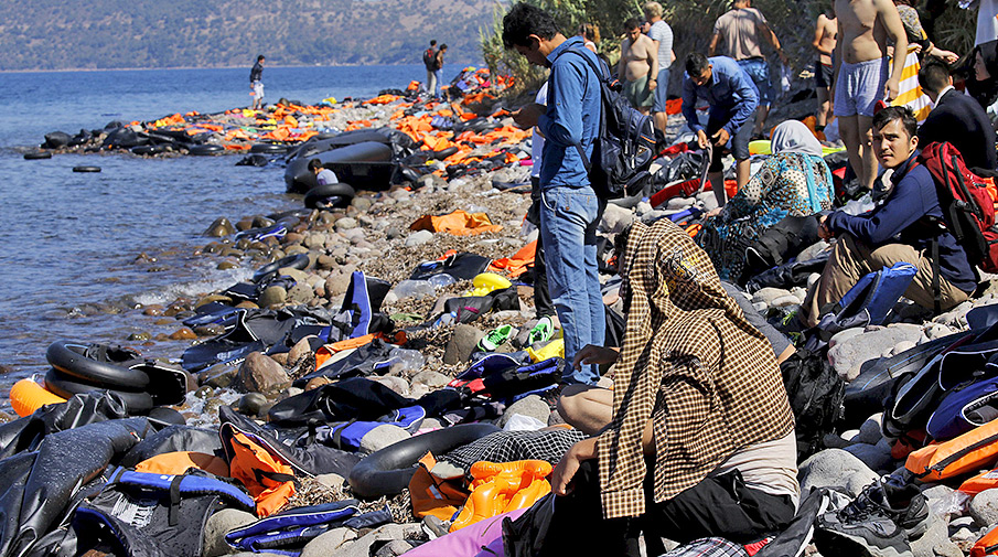 Сотни беженцев из Турции прибывают на лодках на пляж греческого острова Лесбос после пересечения Эгейского моря 