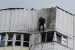 Рабочие устраняют повреждения на крыше многоэтажного жилого дома после атаки беспилотника в Москве, 30 мая 2023 года