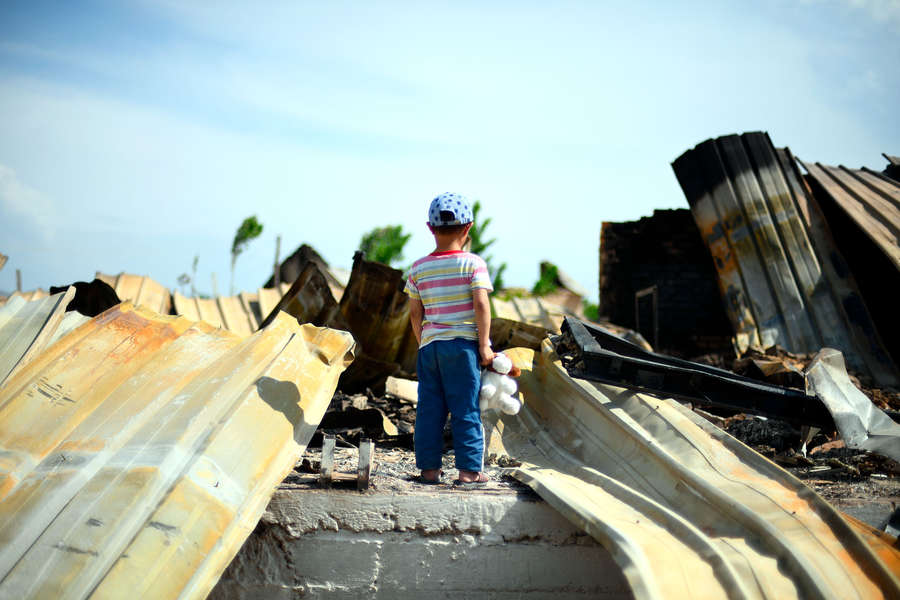Ребенок у сгоревшего здания в селе Максат на границе Киргизии и Таджикистана, май 2021 года
