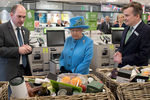 Королева осматривает продуктовые корзины во время посещения магазина