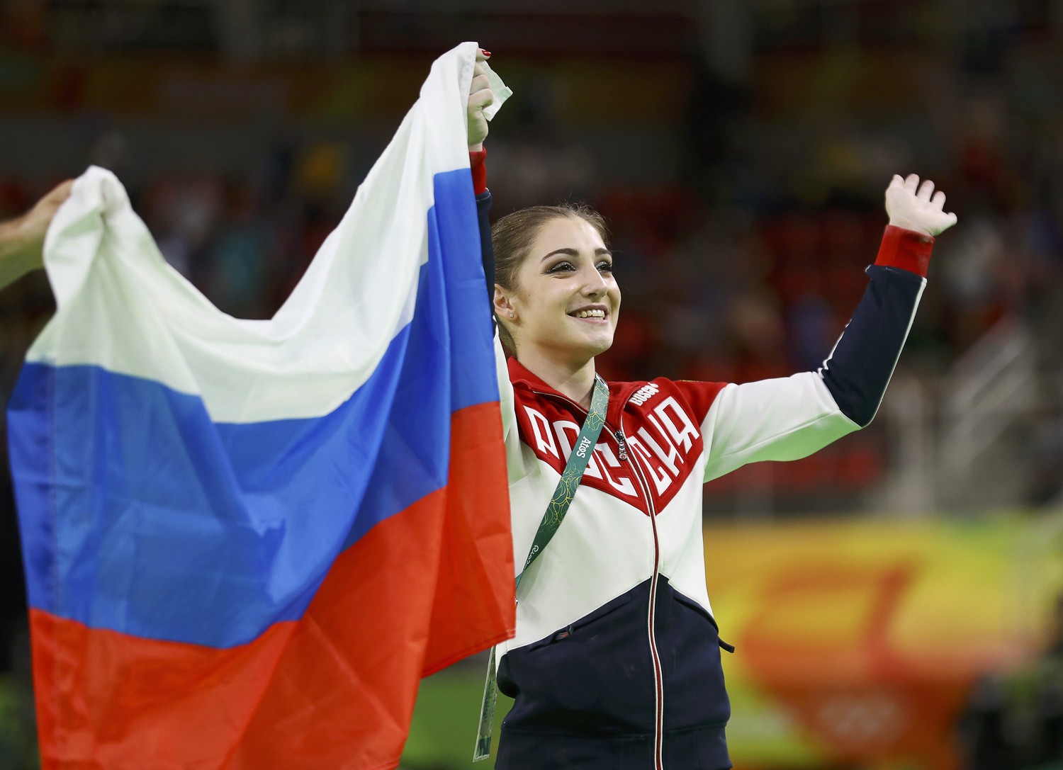 Алия Мустафина с флагом России после победы на Олимпийских играх в соревнованиях на разновысоких брусьях
