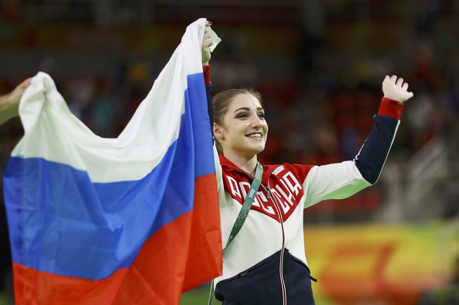 Алия Мустафина с флагом России после победы на Олимпийских играх в соревнованиях на разновысоких брусьях