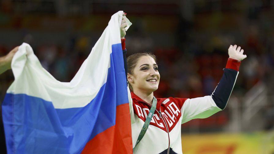 Алия Мустафина с&nbsp;флагом России после победы на&nbsp;Олимпийских играх в&nbsp;соревнованиях на&nbsp;разновысоких брусьях 