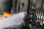 Пожарный тушит горящие автомобильные покрышки, которые подожгли участники акции протеста бойцов батальона «Айдар» и их сторонники у здания министерства обороны Украины в Киеве