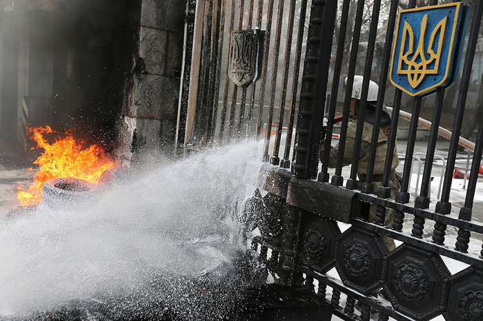 Пожарный тушит горящие автомобильные покрышки, которые подожгли участники акции протеста бойцов батальона &laquo;Айдар&raquo; и их сторонники у&nbsp;здания министерства обороны Украины в&nbsp;Киеве