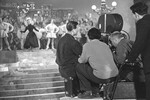<b>Людмила Гурченко (на сцене) в роли Леночки Крыловой на съемочной площадке фильма «Карнавальная ночь».</b>
<br><br>
Музыкальная комедия «Карнавальная ночь» вышла на экраны 29 декабря 1956 года и сразу полюбилась зрителям. Как и образ обаятельной Леночки Крыловой, созданный Людмилой Гурченко в самом начале ее кинокарьеры: на момент съемок картины в багаже 20-летней выпускницы ВГИКа была всего одна небольшая роль в драме «Дорога правды».
<br><br>
Однако первые пробы в «Карнавальную ночь» оказались неудачными. Спела актриса хорошо, но ее внешность из-за плохо выставленного света не впечатлила режиссера Эльдара Рязанова. Поиски исполнительницы главной роли безуспешно продолжались, когда директор «Мосфильма» Иван Пырьев встретил Гурченко в коридоре студии и вновь привел к Рязанову. На этот раз исполнительнице уделили больше внимания – и пробы получились отличными.
